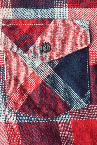 Detail of a red plaid button up style shirt.