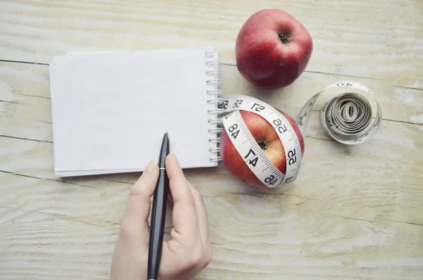 Handschrift im Notizbuch, rote Äpfel und Maßband — Stockfoto