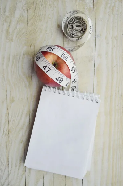 Caderno com fita métrica e uma maçã — Fotografia de Stock