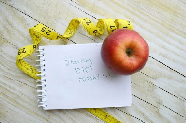 Cuaderno con cinta métrica y una manzana —  Fotos de Stock