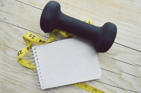 Notebook with measuring tape and dumbbell — Stock Photo, Image