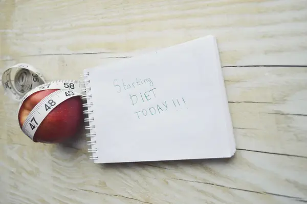 Notebook with measuring tape and an apple — Stock Photo, Image