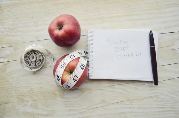 Notitieboekje met meten tape en twee appels — Stockfoto