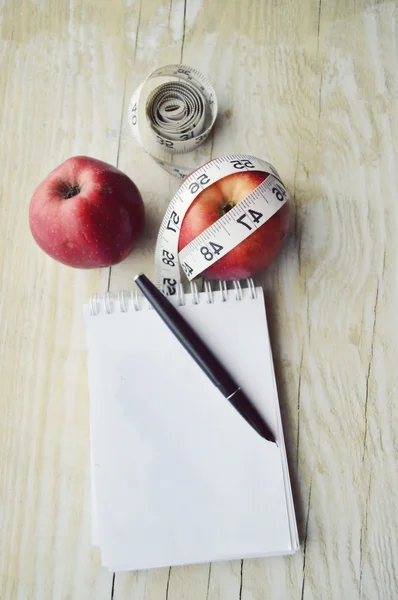 Cuaderno con cinta métrica y dos manzanas — Foto de Stock