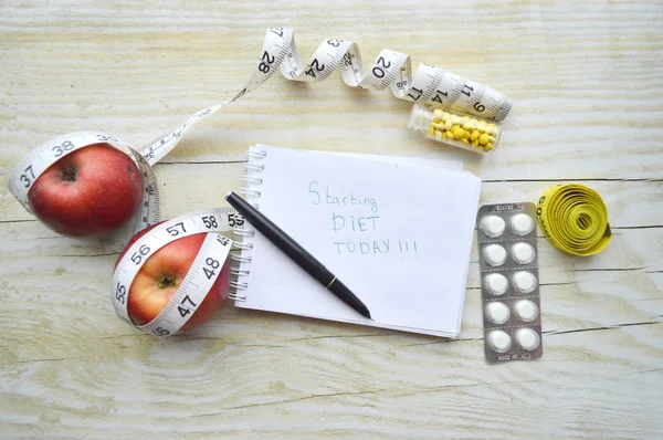 Caderno com fita métrica, duas maçãs e comprimidos — Fotografia de Stock