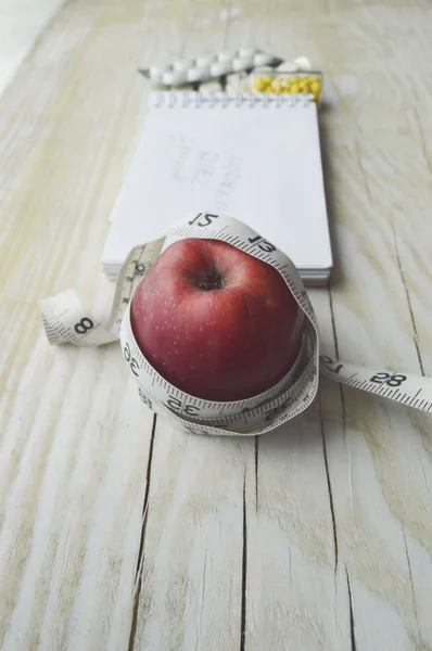 Cuaderno con manzana, pastillas y cinta métrica —  Fotos de Stock