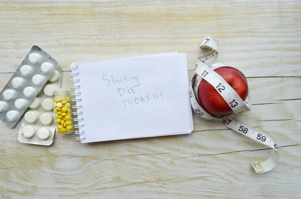 Notebook with apple, pills and measuring tape — Stock Photo, Image