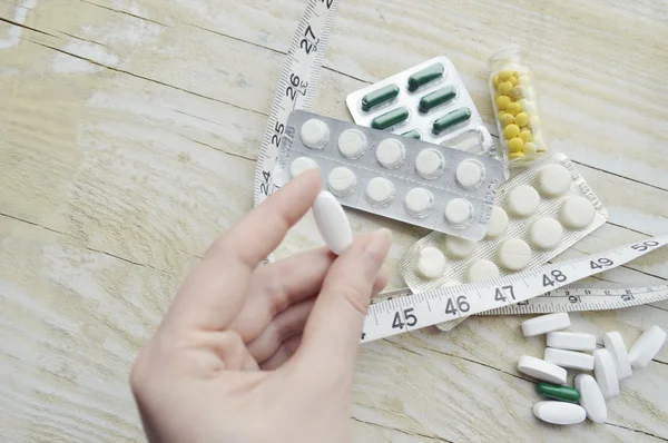 Hand with pills and measuring tape — Stock Photo, Image