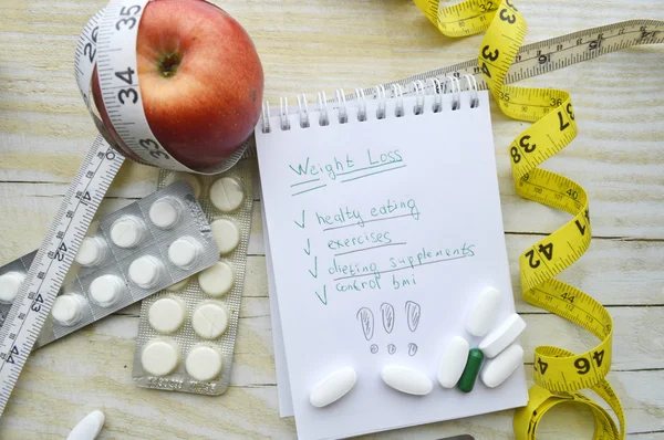 Notizbuch mit Diätplan und Maßband mit Pillen und Apfel — Stockfoto