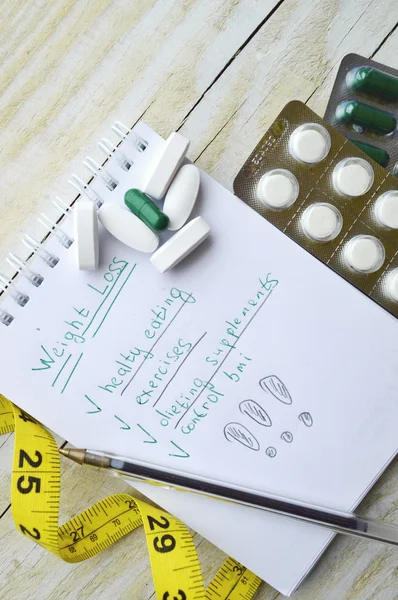 Measuring tape and notebook with pills — Stock Photo, Image