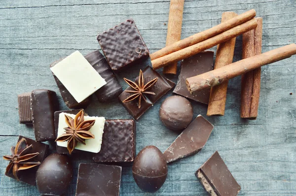 Bar af chokolade, kaffebønner, hasselnødder, valnødder, kanel, koriander, krydderier .chokolade bar, slik barer, forskellige chokolade slik på en træbaggrund - Stock-foto