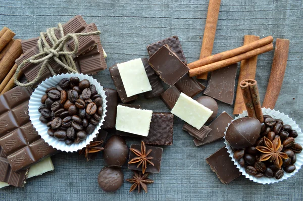 Barra de chocolate, granos de café, avellanas, nueces, canela, cilantro, especias .chocolate barra, barras de caramelo, diferentes dulces de chocolate sobre un fondo de madera — Foto de Stock