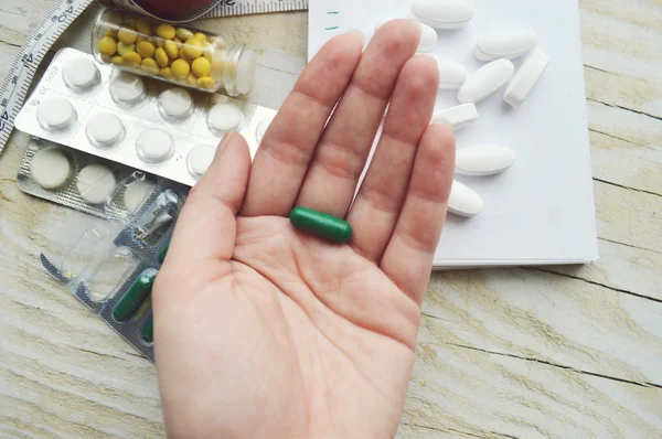 Женская рука с таблетками и блокнот с измерительной лентой — стоковое фото