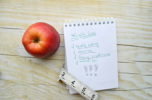 Cuaderno con manzana y cinta métrica —  Fotos de Stock