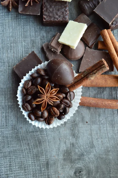 Bar of chocolate, coffee beans, hazelnuts, walnuts, cinnamon, coriander, spices .chocolate bar, candy bars,  different chocolate sweets on a wooden background.big choice of various sweets