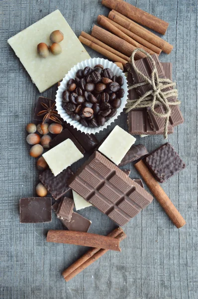 Бар з шоколаду, кавових зерен, лісових горіхів, волоських горіхів, кориці, коріандру, спецій.шоколадні батончики, цукерки, різні шоколадні цукерки на дерев'яному фоні. — стокове фото