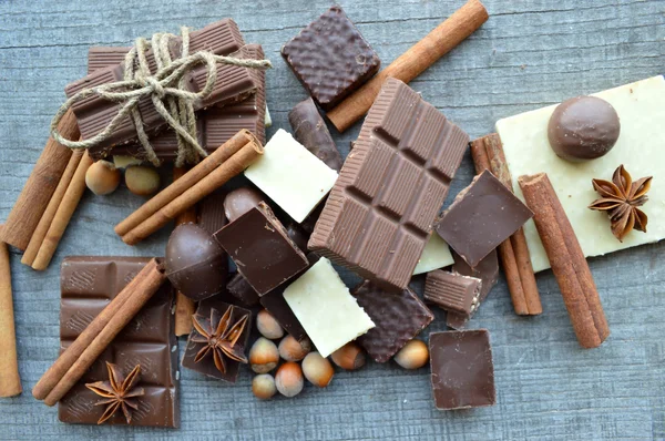 Bar of chocolate, coffee beans, hazelnuts, walnuts, cinnamon, coriander, spices .chocolate bar, candy bars,  different chocolate sweets on a wooden background.big choice of various sweets — Stock Photo, Image