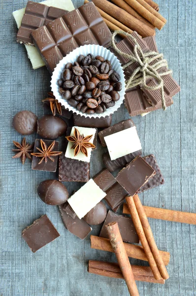 Vários pedaços de chocolate e canela com grãos de café — Fotografia de Stock