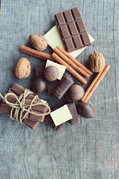 Bar of chocolate, coffee beans, hazelnuts, walnuts, cinnamon, coriander, spices .chocolate bar, candy bars,  different chocolate sweets on a wooden background.big choice of various sweets