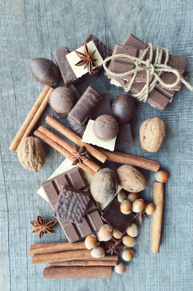 Barretta di cioccolato, chicchi di caffè, nocciole, noci, cannella, coriandolo, spezie. Barretta di cioccolato, barrette di caramelle, diversi dolci al cioccolato su uno sfondo di legno. Grande scelta di vari dolci — Foto Stock