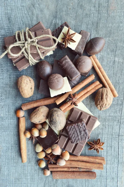 Barre de chocolat, grains de café, noisettes, noix, cannelle, coriandre, épices. Barre de chocolat, barres de bonbons, différents bonbons au chocolat sur un fond en bois. Grand choix de bonbons divers — Photo