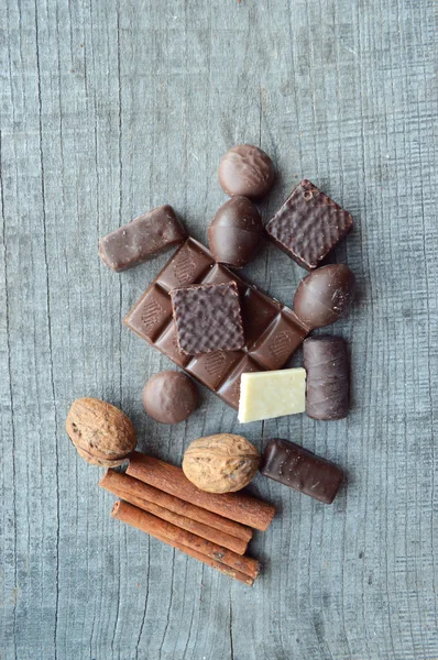 Bar of chocolate, coffee beans, hazelnuts, walnuts, cinnamon, coriander, spices .chocolate bar, candy bars,  different chocolate sweets on a wooden background.big choice of various sweets