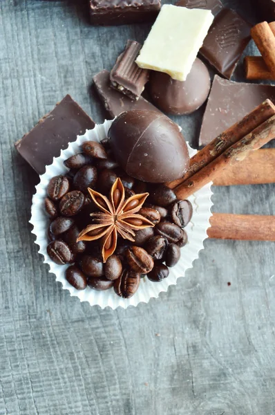 Bar of chocolate, coffee beans, hazelnuts, walnuts, cinnamon, coriander, spices .chocolate bar, candy bars,  different chocolate sweets on a wooden background.big choice of various sweets — Stock Photo, Image