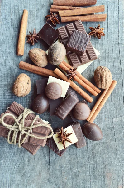 Barra de chocolate, granos de café, avellanas, nueces, canela, cilantro, especias .chocolate barra, barras de caramelo, diferentes dulces de chocolate en un fondo de madera.gran variedad de varios dulces —  Fotos de Stock