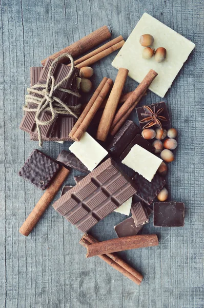 Бар з шоколаду, кавових зерен, лісових горіхів, волоських горіхів, кориці, коріандру, спецій.шоколадні батончики, цукерки, різні шоколадні цукерки на дерев'яному фоні. — стокове фото