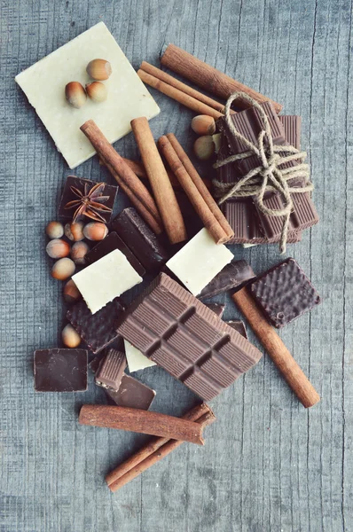 Bar of chocolate, coffee beans, hazelnuts, walnuts, cinnamon, coriander, spices .chocolate bar, candy bars,  different chocolate sweets on a wooden background.big choice of various sweets — Stock Photo, Image