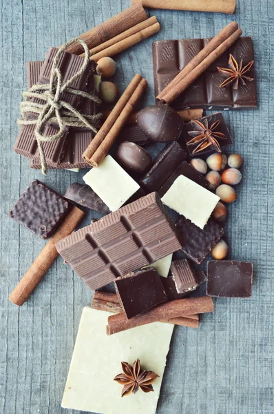 Barre de chocolat, grains de café, noisettes, noix, cannelle, coriandre, épices. Barre de chocolat, barres de bonbons, différents bonbons au chocolat sur un fond en bois. Grand choix de bonbons divers — Photo