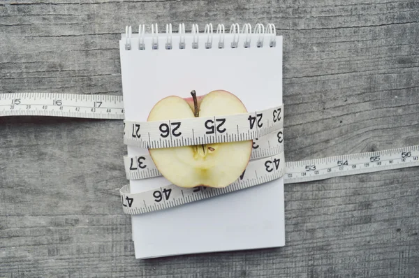 Cuaderno vacío con media manzana y cinta métrica — Foto de Stock