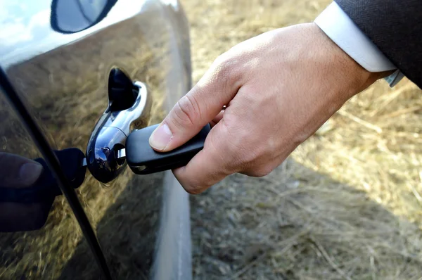 Mano masculina con llaves del coche abriendo la puerta del coche —  Fotos de Stock