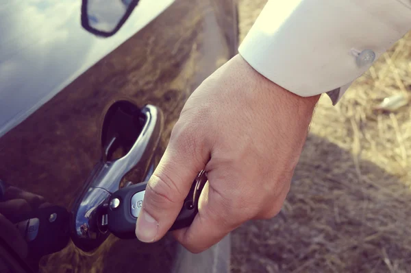 Main masculine avec clés de voiture ouvrant la porte de la voiture — Photo