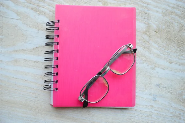 Caderno com óculos na mesa de madeira — Fotografia de Stock