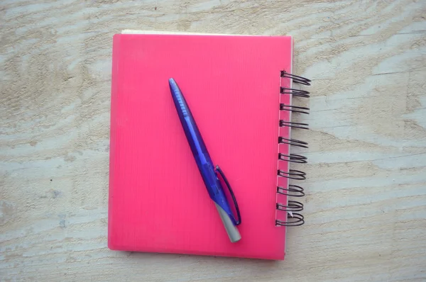 Cuaderno con un bolígrafo sobre mesa de madera — Foto de Stock