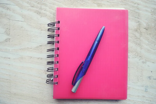 Cuaderno con un bolígrafo sobre mesa de madera — Foto de Stock