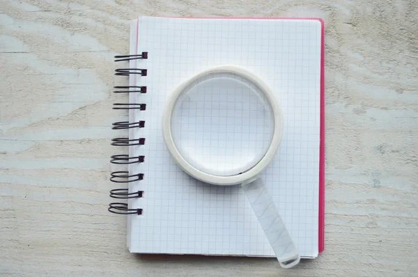 Notebook with magnifying glass — Stock Photo, Image