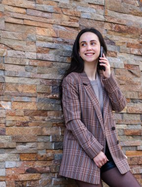 Kız telefonda konuşuyor, duvara yaslanıyor.