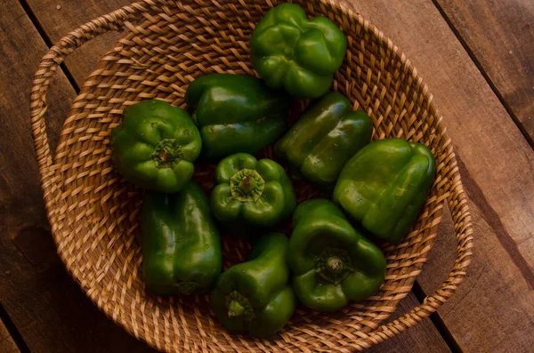 green bell peppers on wicker tray and wooden floor viewed from above very green