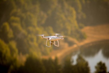 Beyaz dron dağın tepesinde uçuyor, uzaktan çekim yapıyor ve fotoğraf çekiyor.