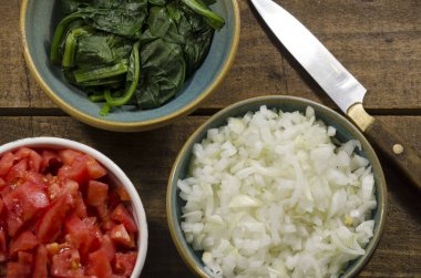 Domates, seboolla, ıspanak, ahşap sebzeler.