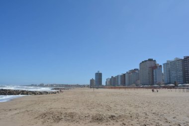 Deniz kıyısı, kum ve gökyüzü. Arka planda şehir, Miramar.