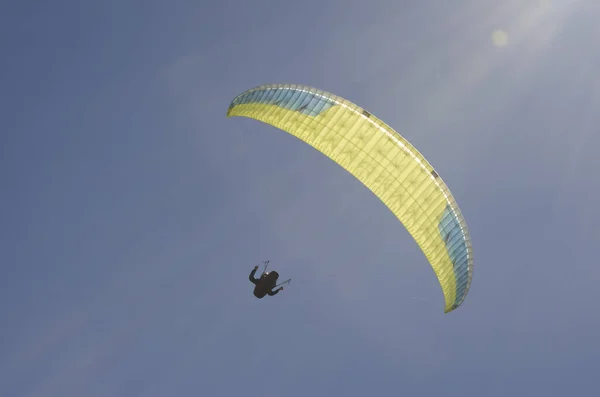 背光滑翔伞飞行与太阳和蓝天照明已部署的降落伞 — 图库照片