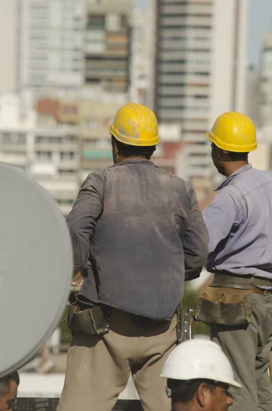 2人の建設労働者が作業服を着て高さの高い建物の建設に取り組み — ストック写真