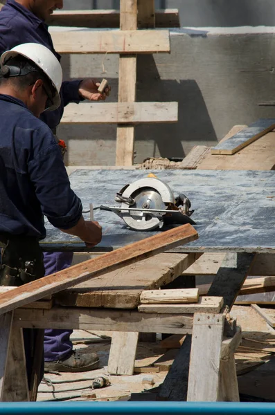 建筑工人穿着工作服 黄色头盔 眼镜和其他工具 用圆锯切割 — 图库照片