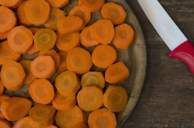 plate with cut carrots seen from above. ingredient for salad or healthy meals with ceramic knife on the side