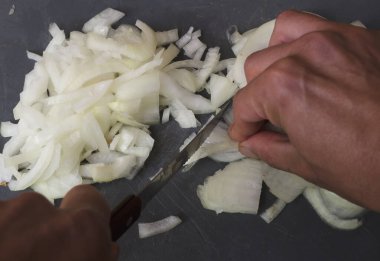 Lezzetli yemekler için jülyen tahtasında soğan doğrayan eller.