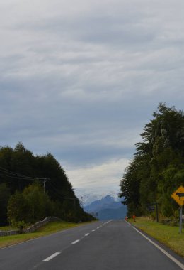 Dağ yolunda, dağ sırasının sağında bir işaret levhası var.
