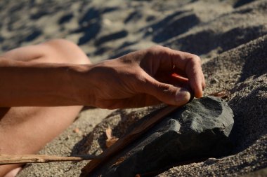 Dal, kök ve taştan ateş yakıyor. Çakmak olmadan. Dışarıda, kumda.